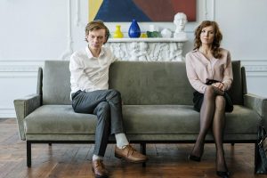 woman in white dress shirt and black pants sitting on gray couch